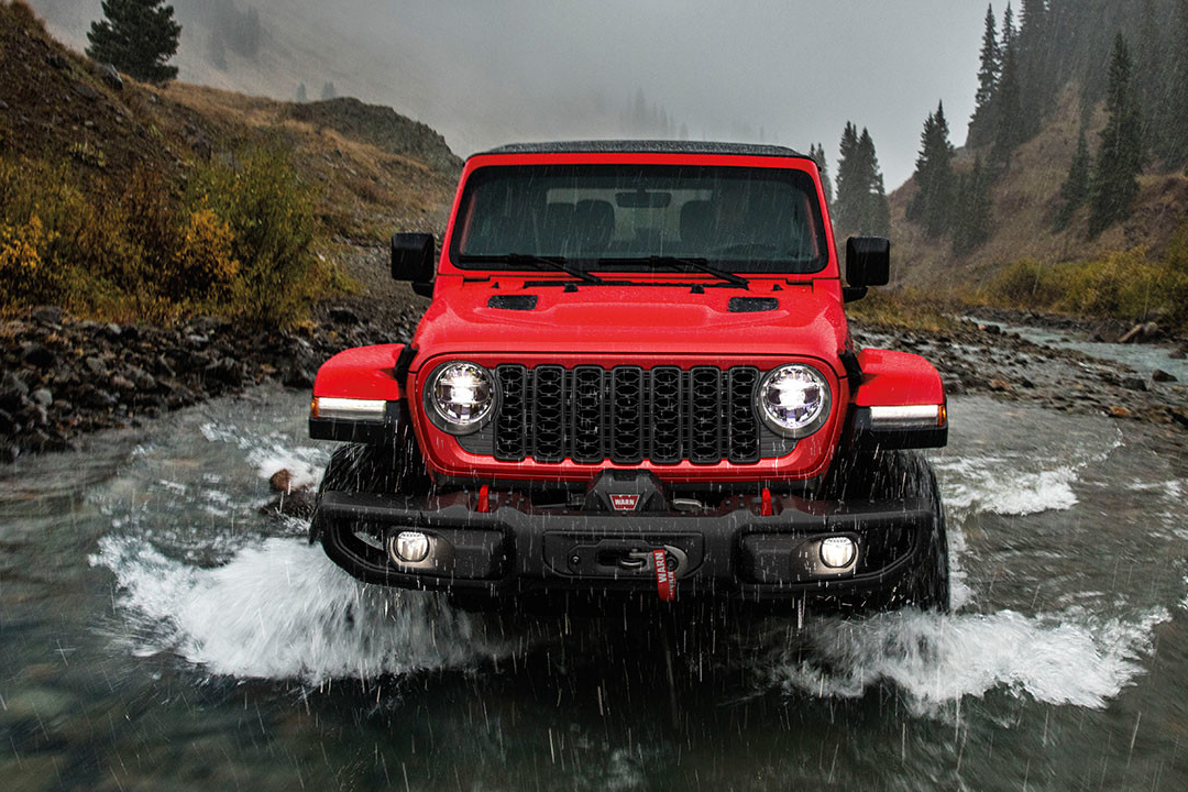 Front view of Jeep Wrangler 2024 crossing a river on a rainy day